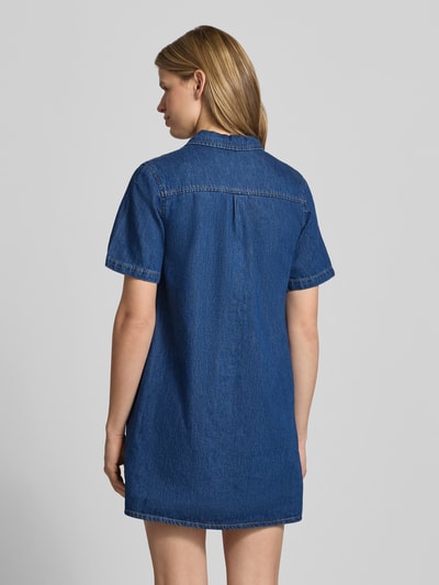 Frauenmodel trägt Relaxed Fit Minikleid in Denim-Optik Modell 'Amara' von JJXX aus reiner Baumwolle, kurzärmelig, Umlegekragen, Ganzkörperansicht Rückansicht.
