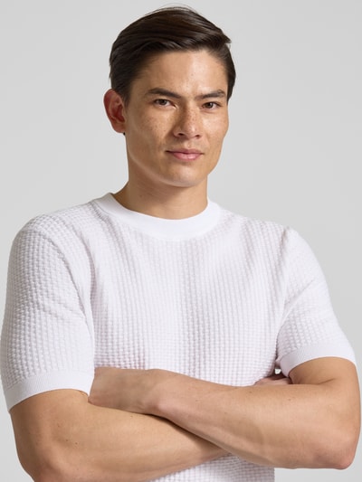 Männermodel trägt Regular Fit Strick-Shirt aus reiner Baumwolle Modell 'H-NILTON' von BOSS, weiß, strukturierte Oberfläche, Nahaufnahme Oberkörper.
