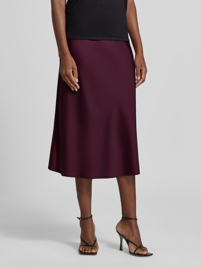 Frauenmodel trägt Midirock mit elastischem Bund Modell 'PELLA' von YAS aus bordeauxfarbenem Satin, A-Linie, Nahaufnahme Oberkörper.