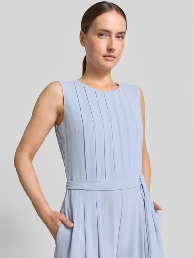Frauenmodel trägt Regular Fit Jumpsuit mit Viskosefutter von s.Oliver BLACK LABEL, aus hellblauem Chiffon mit Bindegürtel und Rundhals, Nahaufnahme Oberkörper.