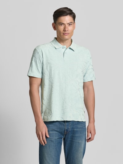 Männermodel trägt Regular Fit Poloshirt aus Baumwoll-Mix Modell 'PE_FLOWER' von BOSS Orange, Optik: Allover-Muster, Struktur, Ganzkörperansicht von vorne.