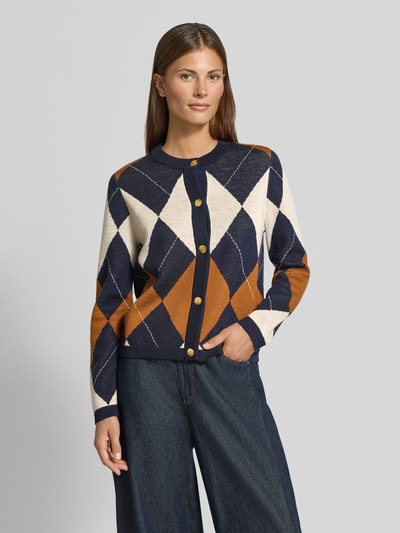 Frauenmodel trägt Regular Fit Strickjacke aus reiner Wolle von GANT in Dunkelblau, Weiß und Braun mit Rauten-Muster, Nahaufnahme Oberkörper. Damen Strickjacke