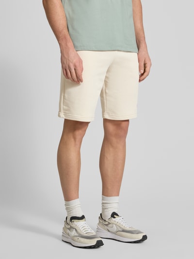Männermodel trägt Shorts mit Label-Stitching von PUMA PERFORMANCE, cremefarben, Baumwoll-Mix, elastischer Bund, Ganzkörperansicht von vorne.