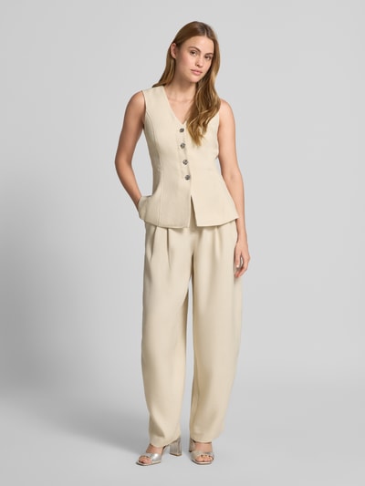 Modelka nosi Weste aus Viskose-Mix mit Knopfleiste Modell 'Esteriane' od MSCH Copenhagen, beżowa, krój slim fit, V-dekolt, całkowite ujęcie z przodu.