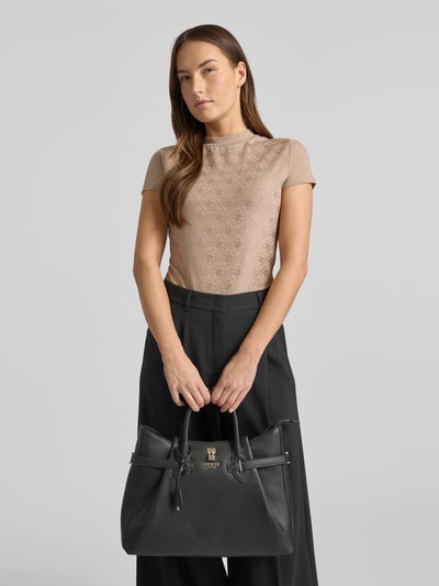 Kobiece model prezentuje Handtasche in Leder-Optik mit Logo-Applikation von Guess w kolorze czarnym z logo, uchwyty, odpinany pasek, widok z przodu, zdjęcie całej sylwetki.