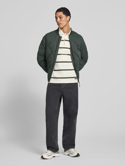 Männermodel trägt Regular Fit Steppjacke mit Opstaande kraag van Superdry in donkergroen met Stiksels, Steekzakken, elastische mouwboorden, ritssluiting, regular fit; Ruglengte maat M 69 cm, Schouderbreedte 46 cm, Borstwijdte 58 cm, Mouwlengte 59 cm, Ganzkörperansicht van voren.