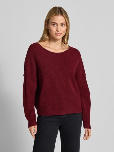Frauenmodel trägt Relaxed Fit Strickpullover aus Material-Mix mit Leinen-Anteil von American Vintage in Dunkelrot, gerippte Abschlüsse, überschnittene Schultern, langärmlig, Rundhalsausschnitt, Ganzkörperansicht von vorne.