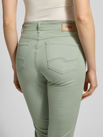 Kobiece model prezentuje jeansy z mieszanki bawełny z dodatkiem streczu, krój slim fit, wpuszczane kieszenie, Jeansy z wpuszczanymi kieszeniami model 'Ornella' od Angels, szerokość w rozmiarze 36: 40 cm, długość wewnętrzna nogawki w rozmiarze 36: 67 cm, zielony odcień, gładka faktura, widok całej sylwetki z tyłu.