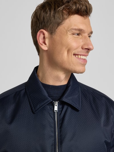 Männermodel trägt Regular Fit Blouson mit Logo-Muster Modell 'H-CRESTELL' von BOSS in Dunkelblau, sichtbare Textur, Nahaufnahme Oberkörper.