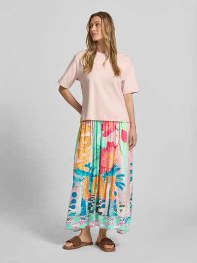 Frauenmodel trägt Midirock aus reiner Viskose mit Allover-Motiv-Print von miss goodlife in bunten Farben, A-Linie, elastischer Bund, Ganzkörperansicht von vorne.