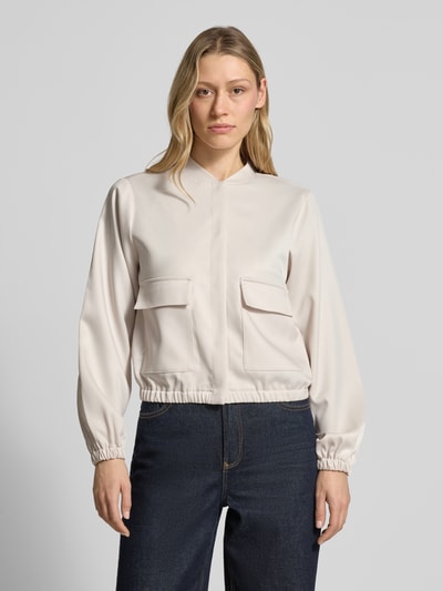 Frauenmodel trägt Bomberjacke aus Satin mit Pattentaschen von monari in Beige mit elastischen Abschlüssen, Ganzkörperansicht von vorne.