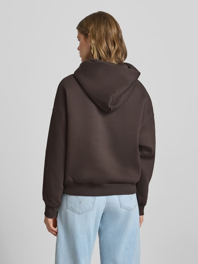 Modelka nosi Hoodie mit Logo und Känguru-Tasche von Review, mieszanka bawełny, krój relaxed fit, logo, kieszeń kangurka, widok całej sylwetki z tyłu
