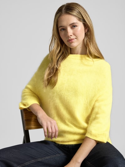 Modelka kobieca nosi Strickpullover aus Kaschmir-Baumwoll-Mix mit 3/4-Arm od HERZENS, krój regular fit, okrągły dekolt, długość tyłu 63 cm, długość rękawa 30 cm, jasny żółty sweter, tekstura miękka i puszysta, zbliżenie na górną część ciała
