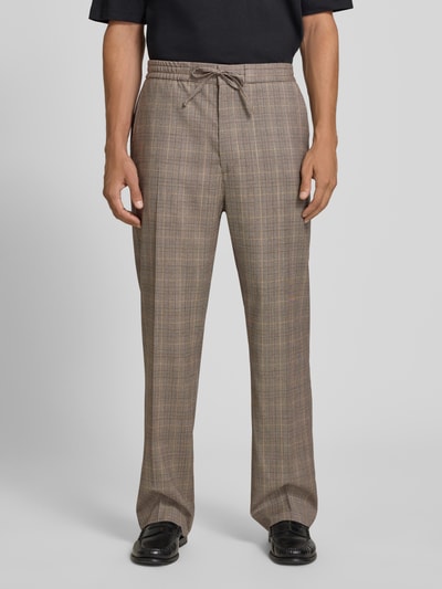 Mężczyzna nosi spodnie materiałowe Straight Fit Stoffhose mit Bügelfalten Modell 'Cove' von Tiger Of Sweden z bawełny, wzór w kratę, kanty, wpuszczane kieszenie, kieszeń z tyłu, elastyczny pas z tunelem, szerokość w rozmiarze 50: 39 cm, długość wewnętrzna nogawki 80 cm, widok całej sylwetki z przodu.