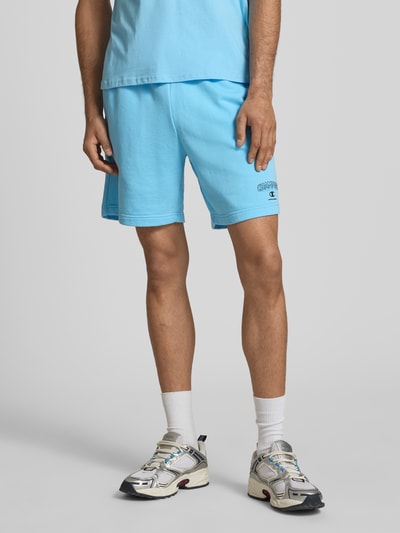 Männermodel trägt Sweatshorts mit Logo und elastischem Bund von CHAMPION in Hellblau, Baumwoll-Mix, Regular Fit, Nahaufnahme Oberkörper bis Knie.
