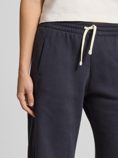 Frauenmodel trägt dunkelblaue Sweatpants mit elastischem Bund und Tunnelzug von Review, Baumwoll-Mix mit Viskose-Anteil, Nahaufnahme Oberkörper.