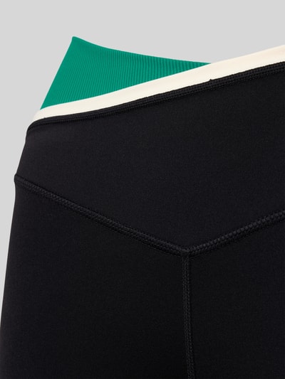 Frauenmodel trägt Slim Fit Leggins mit Logo-Print von P.E Nation, elastischer Material-Mix, schwarzer Stoff, Nahaufnahme Hüfte.