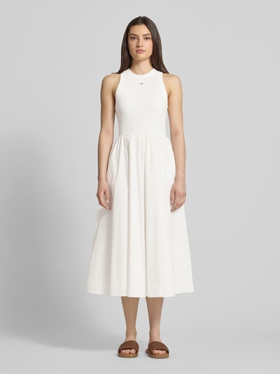 Vrouwenmodel draagt Midikleid aus reiner Baumwolle van Tommy Jeans, effen wit, a-lijn fit, mouwloos, ronde hals, midi lengte, pure katoen, volledige lichaamsvoorzijde.