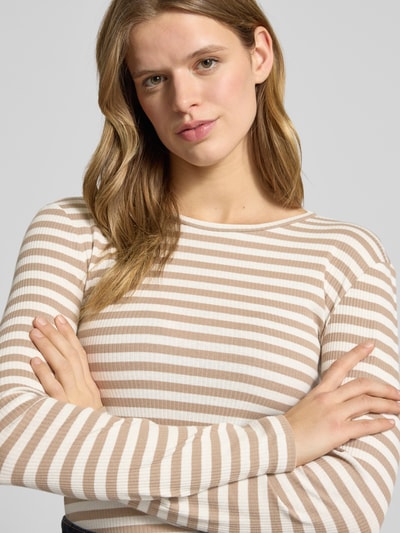 Modelka nosi Slim Fit Langarmshirt aus Baumwoll-Mix von Pieces, wzór w paski, two tone, rippstrick, kolor beżowo-biały, krój slim fit, dekolt okrągły, długi rękaw, bawełniany mix, zbliżenie na górną część ciała.
