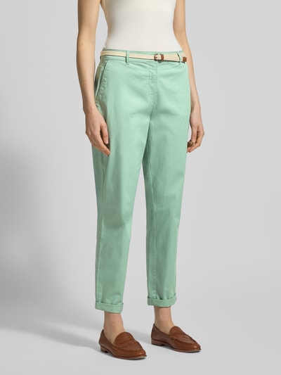 Modelka nosi Casual Fit Chino mit Baumwoll-Anteil od Christian Berg Woman, mięta, pasek, mieszanka bawełny, zapięcie na guzik i zamek błyskawiczny, kieszenie boczne i z tyłu, skrócony fason, szerokość w rozmiarze 36: 41 cm, długość wewnętrzna nogawki w rozmiarze 36: 70 cm, stylizacje casualowe, widok całej sylwetki z przodu.