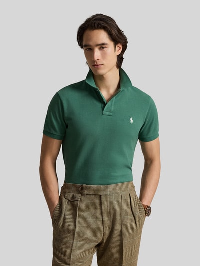 Männermodel trägt Regular Fit Poloshirt aus reiner Baumwolle von Polo Ralph Lauren in Grün, unifarben, Piqué-Textur, Ganzkörperansicht von vorne.