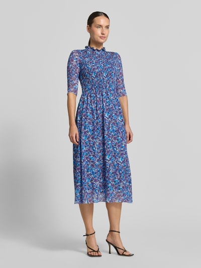 Kobiece modelka nosi sukienkę midi z marszczonym detalem od Rich & Royal, elastyczna mieszanka materiałów, taliowany krój, stójka z obszyciem falbanami, rękaw o dł. 1/2, kwiatowy nadruk na całej powierzchni, Długość tyłu w rozmiarze S: 120 cm, Szerokość w rozmiarze S: 34 cm, Długość rękawów w rozmiarze S: 36 cm, widok całej sylwetki z przodu.