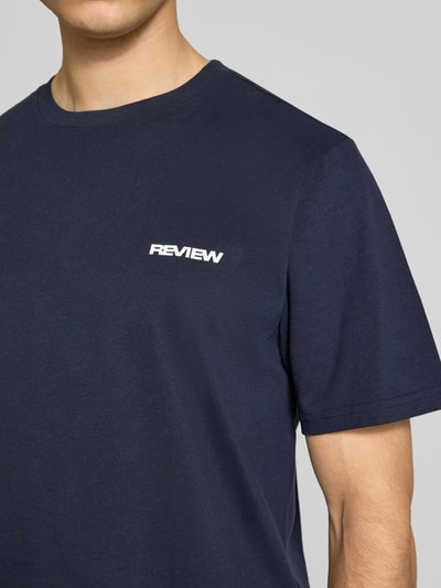 Männermodel trägt T-Shirt mit Logo und Rundhalsausschnitt von REVIEW in Dunkelblau aus Baumwoll-Viskose-Mix, Regular-Fit, Nahaufnahme Oberkörper. Rückenlänge bei Größe M: 64 cm.