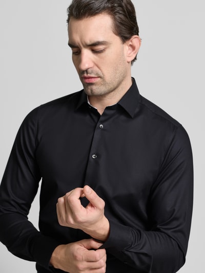 Männermodel trägt Slim Fit Business Hemd aus Baumwolle mit Kentkragen von OLYMP, Schwarz, glatte Textur, Nahaufnahme Oberkörper, Baumwoll-Elasthan-Mix, Knopfleiste.