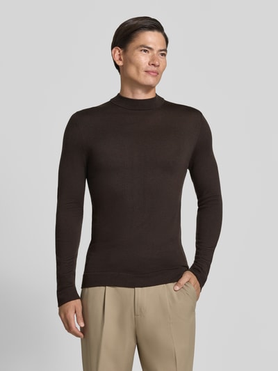 Männermodel trägt Slim Fit Longsleeve aus reiner Schurwolle Modell 'Arwon' von DRYKORN, dunkles Braun, glatte Textur, Ganzkörperansicht von vorne. Rückenlänge bei Größe M 67 cm, Ärmellänge 68 cm, Stehkragen.