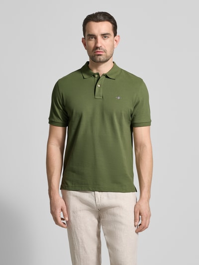 Männermodel trägt Slim Fit Poloshirt mit Logo-Stitching von Gant aus Reine Baumwolle, Polo-Kragen, Kurzärmelig, Ganzkörperansicht von vorne.