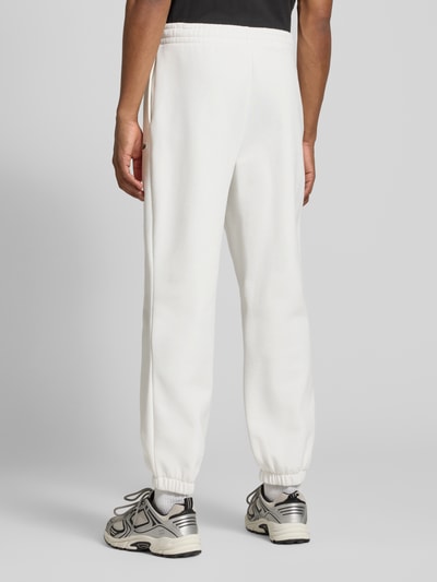 Männermodel trägt Regular Fit Sweathose aus Baumwoll-Mix von Lacoste in Weiß mit glatter Struktur, Herren Sweathose, Ganzkörperansicht Rückansicht.