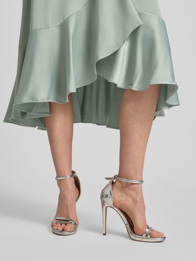 Frauenmodel trägt Cocktailkleid mit Volantsaum Modell 'THEA' von YAS aus mintgrünem Satin, Midikleid, Detailaufnahme Beine.