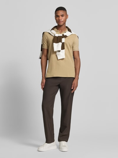 Męski model nosi Slim Fit Poloshirt aus Baumwoll-Mix von Polo Ralph Lauren, efekt: jednolity kolor, krój slim fit, detal z logo, kołnierzyk polo, dekolt w serek, bez zapięcia, krótki rękaw, zakończenie rękawów prążkowane, wykończenie z bocznymi rozcięciami, asymetryczny dół, wykończenie materiału: pika, mieszanka bawełny, widok całej sylwetki z przodu.