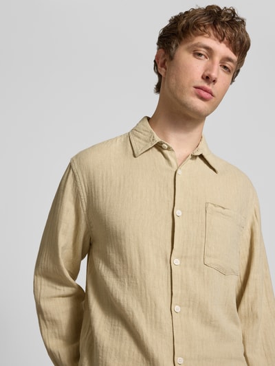 Männermodel trägt Slim Fit Freizeithemd aus Leinen-Baumwoll-Mix Modell 'NELSON' von Redefined Rebel, helle Beige-Töne, Nahaufnahme Oberkörper, Kontext: Herren Freizeithemd, Kentkragen, Brusttasche, Label-Detail, Rückenlänge bei Größe M 50 cm, Schulterbreite 49 cm, Ärmellänge 72 cm.