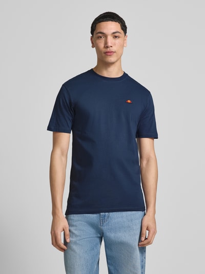Męski model nosi T-Shirt mit Label-Stitching Modell 'CASSICA' od Ellesse, bawełna, krój regular fit, okrągły dekolt, granatowy, całkowita długość z tyłu w rozmiarze M: 71 cm, widok całej sylwetki od przodu.