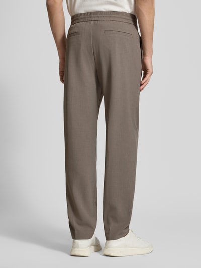 Männermodel trägt Relaxed Fit Hose mit elastischem Bund von Lindbergh aus Material-Mix mit Viskose-Anteil in Beige, Ganzkörperansicht Rückansicht.