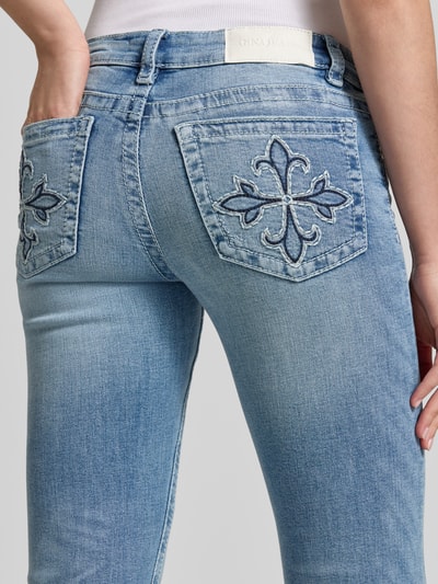 Frauenmodel trägt Flared Jeans im Used-Look Modell 'Poppy' von Gina Tricot mit 5-Pocket-Design aus Baumwoll-Mix, Detailaufnahme Rückansicht.