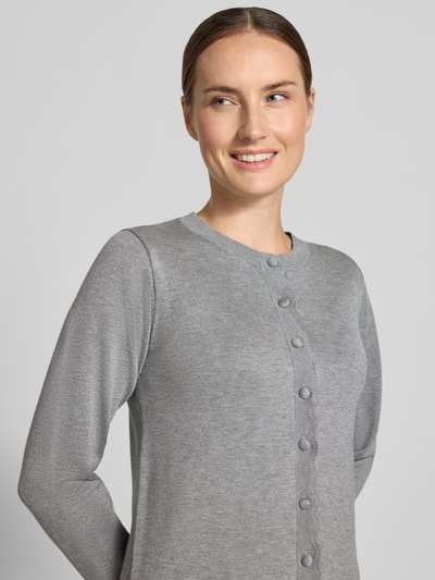 Frauenmodel trägt Strickjacke aus Viskose-Mix Modell 'MORLA' von b.young in Hellgrau, Knopfleiste, glatte Textur, Nahaufnahme Oberkörper, Damen Strickjacke, gerader Schnitt, elastische Ärmelabschlüsse mit Muschelsaum.