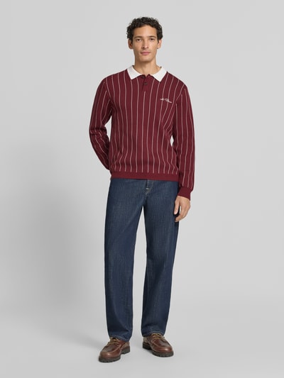 Männermodel trägt Regular Fit Poloshirt mit Logo-Stitching von Les Deux, Baumwolle, Polokragen, rote Farbe, Ganzkörperansicht von vorne.