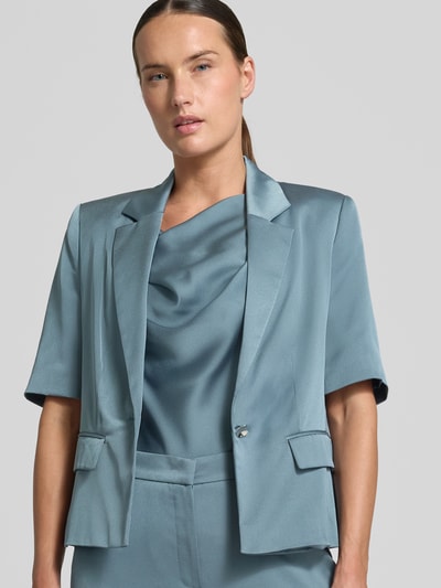Frauenmodel trägt Slim Fit Blazer mit 1/2-Arm von SWING, Reverskragen, Pattentaschen, seidig glänzende Textur, Nahaufnahme Oberkörper.