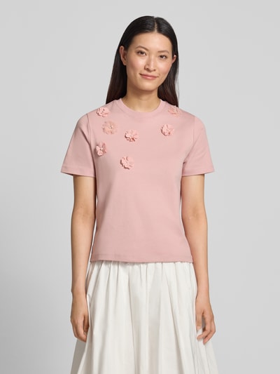 Frauenmodel trägt T-Shirt mit floralen Applikationen von Christian Berg Woman in Rosa, Reine Baumwolle, Gerader-Schnitt, Rundhalsausschnitt, 1/2-Arm, Rückenlänge 52 cm, Ganzkörperansicht von vorne.