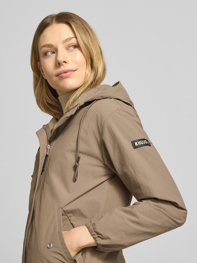 Kobiece model nosi parka o prostym kroju z kapturem i naszywką z logo, model 'AMETI' od khujo, zbliżenie na górną część ciała