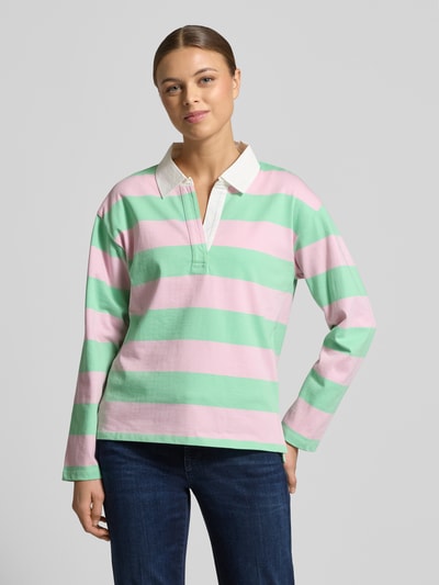 Frauenmodel trägt Regular Fit Poloshirt aus reiner Baumwolle von s.Oliver RED LABEL in grün-rosa-weiß gestreift, Langarm, Piqué, Ganzkörperansicht von vorne.