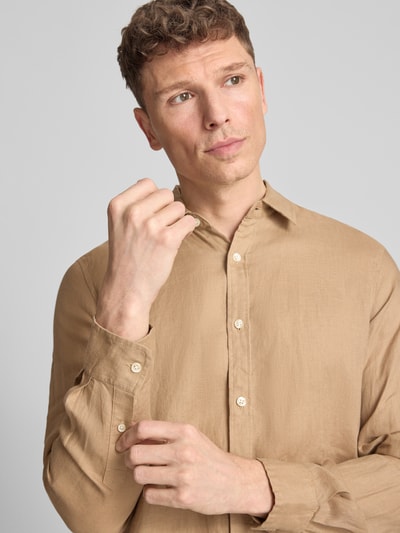 Mannenmodel draagt Regular Fit Leinenhemd aus reinem Leinen Modell 'CORE' van Scotch & Soda in effen lichtbruin met doorlopende knoopsluiting, met lange mouwen, labelstitching en kentkraag, detailaufnahme bovenlichaam. Context: heren linnenoverhemd, regular fit, ruglengte maat M 78 cm, schouderbreedte 45 cm, mouwlengte 66 cm.