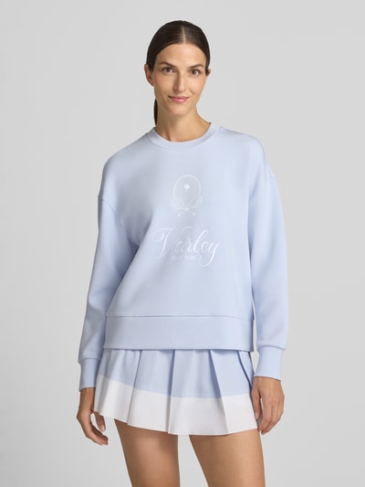 Frauenmodel trägt Sweatshirt aus Viskose-Mix Modell 'rasco' von VARLEY in Hellblau mit geripptem Rundhalsausschnitt, elastischen Abschlüssen, Label-Stickerei und lockerer Passform, Ganzkörperansicht von vorne.