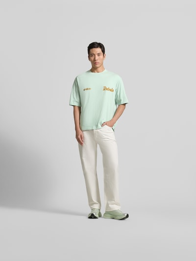 Männermodel trägt Loose Fit T-Shirt mit Logo-Stitching von Dsquared2, pastellgrün, Statement-Stitching, Ganzkörperansicht von vorne.