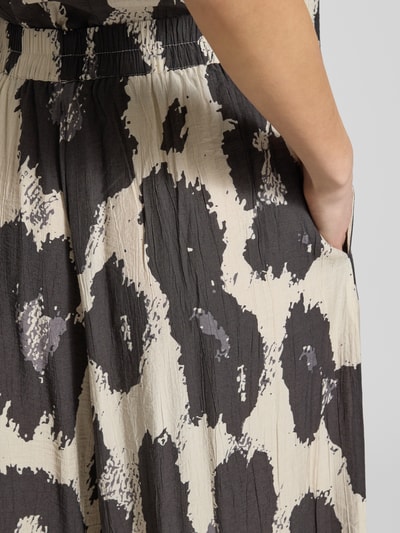 Kobiece modelka nosi spodnie z szerokimi nogawkami MSCH Copenhagen Wide Leg Hose aus Viskose-Mix Modell 'Karalie Jusia' w czarno-beżowe plamy, mieszanka wiskozy, elastyczny pas, skrócona nogawka, szerokość w rozmiarze S: 91 cm, długość wewnętrzna nogawki: 61 cm, zbliżenie na kieszeń, detal tkaniny.