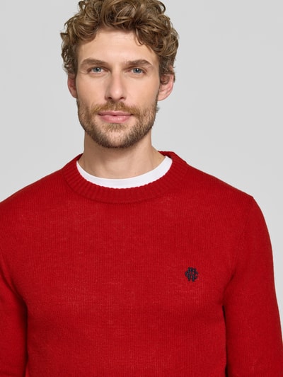 Männermodel trägt Slim Fit Strickpullover aus reiner Wolle mit Label-Stitching von MCNEAL, gerippte Abschlüsse, Nahaufnahme Oberkörper.