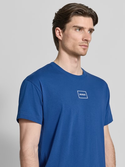 Männermodel trägt Regular Fit T-Shirt aus Baumwoll-Mix Modell 'LAZE T-SHIRT' von HUGO in Blau mit Label Print, Nahaufnahme Oberkörper.