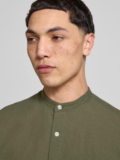 Männermodel trägt koszulę casualową Jack & Jones z mieszanki bawełny i lnu, model 'BREEZE', krój regular fit, stójka, listwa guzikowa, kolor oliwkowy, widoczna faktura materiału, Nahaufnahme górnej części torsu